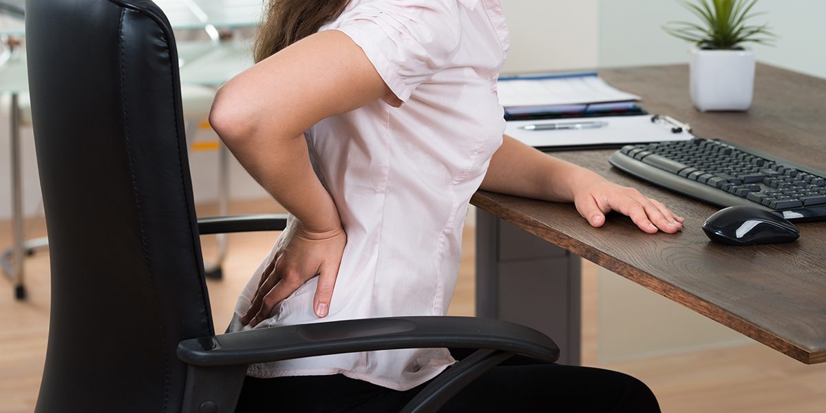 Close-up Of Young Businesswoman On Chair Having Backpain In Office