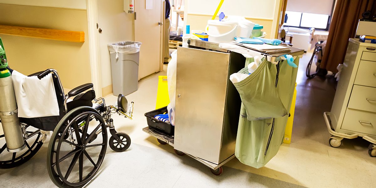 A hospital room with a clean cart and wheelchair.