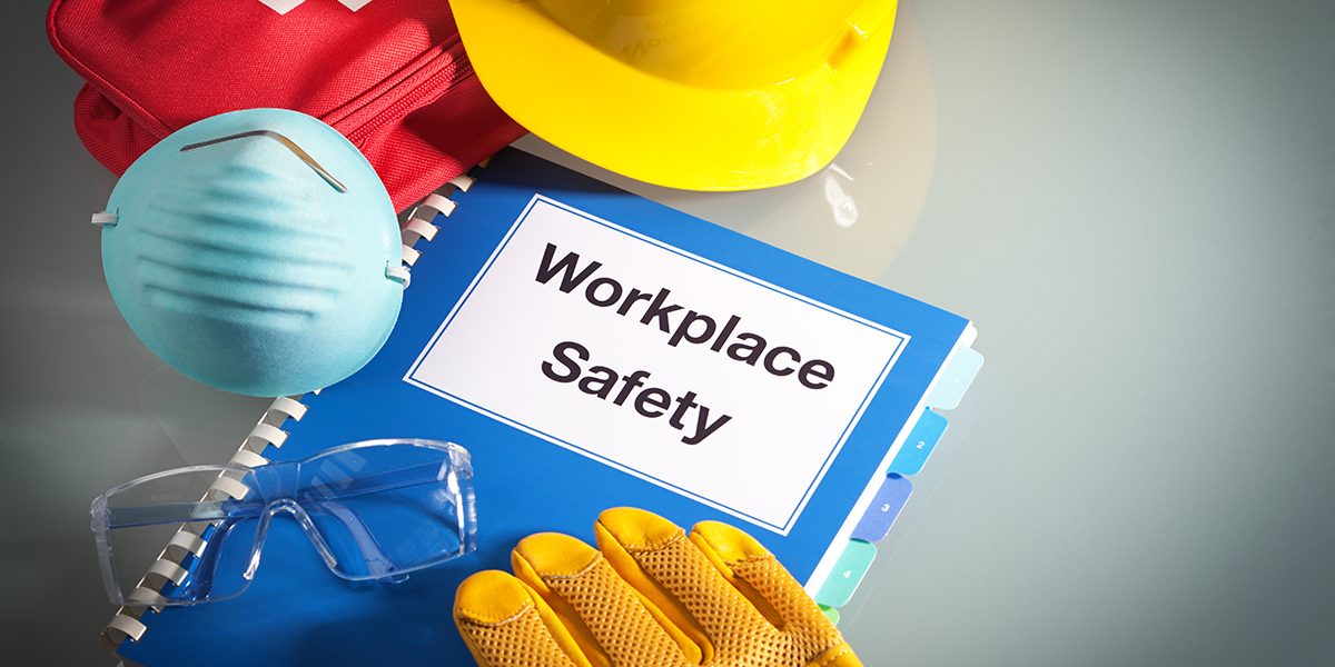 Workplace safety handbook with occupational safety equipment still life, a work training class and instruction manual for using safety equipment and administering first aid. Employment education document with protective eyewear, hard hat, first aid kit, work glove, and pollution mask. Guidance and planning tools in horizontal format with copy space.